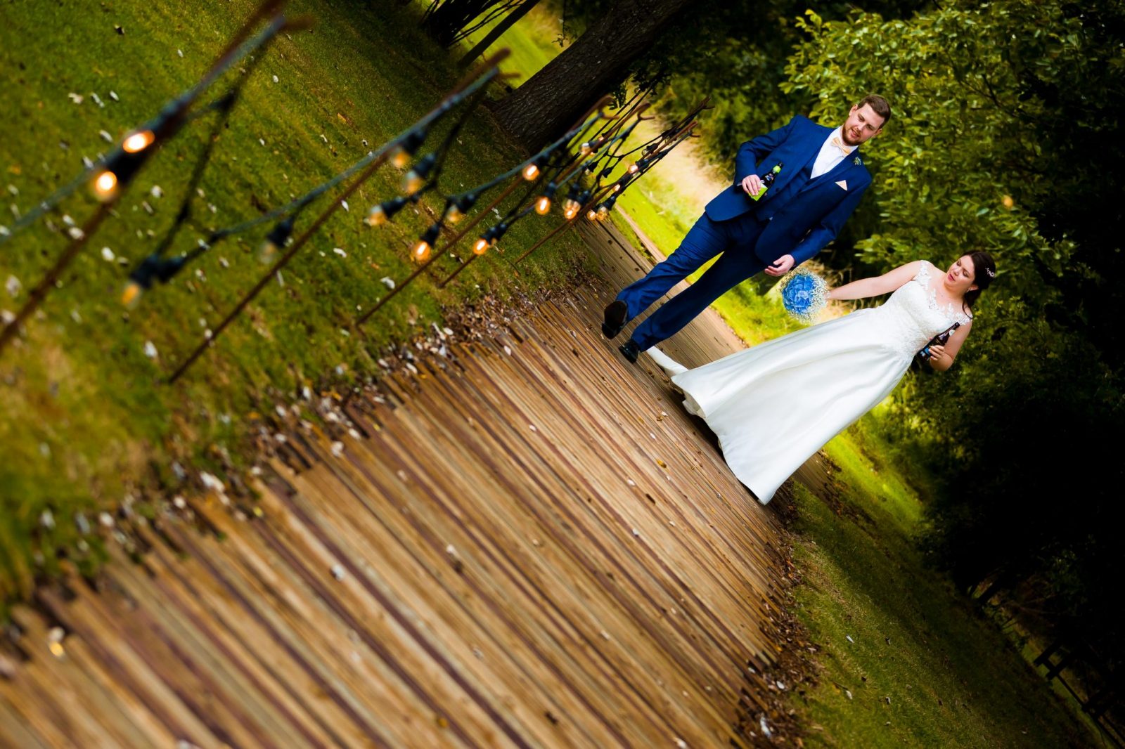 Bride and groom walking hand in hand along the wooden path to the tipi