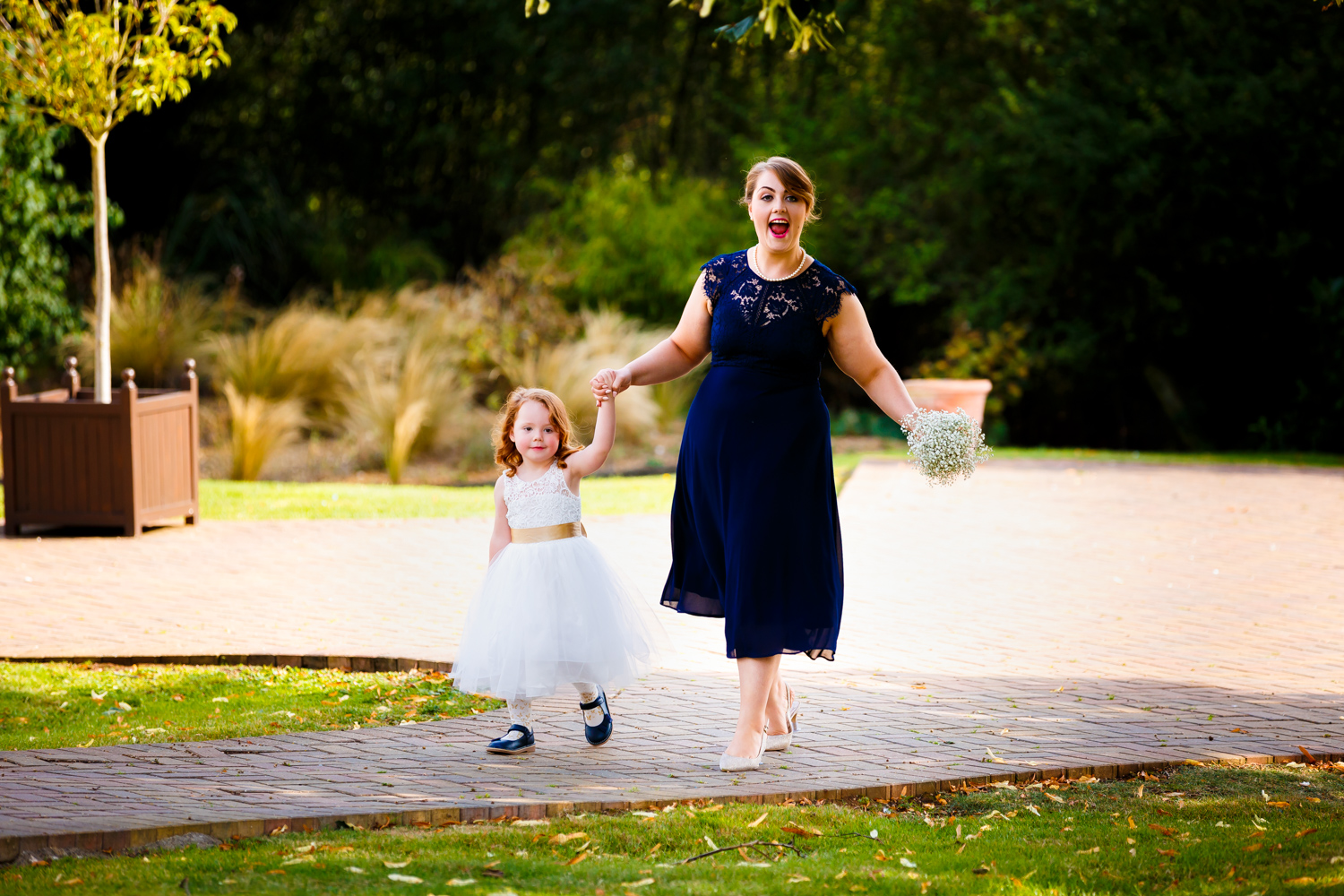 Flower girl and bridesmaid walking hand in hand