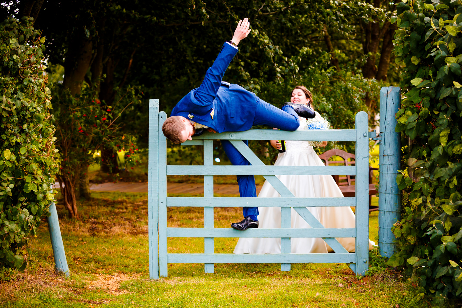 Groom falling over a wooden fence into a field