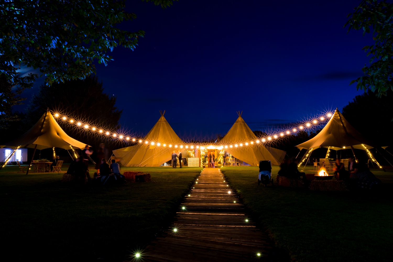 Tipi at night with glowing lights and fire