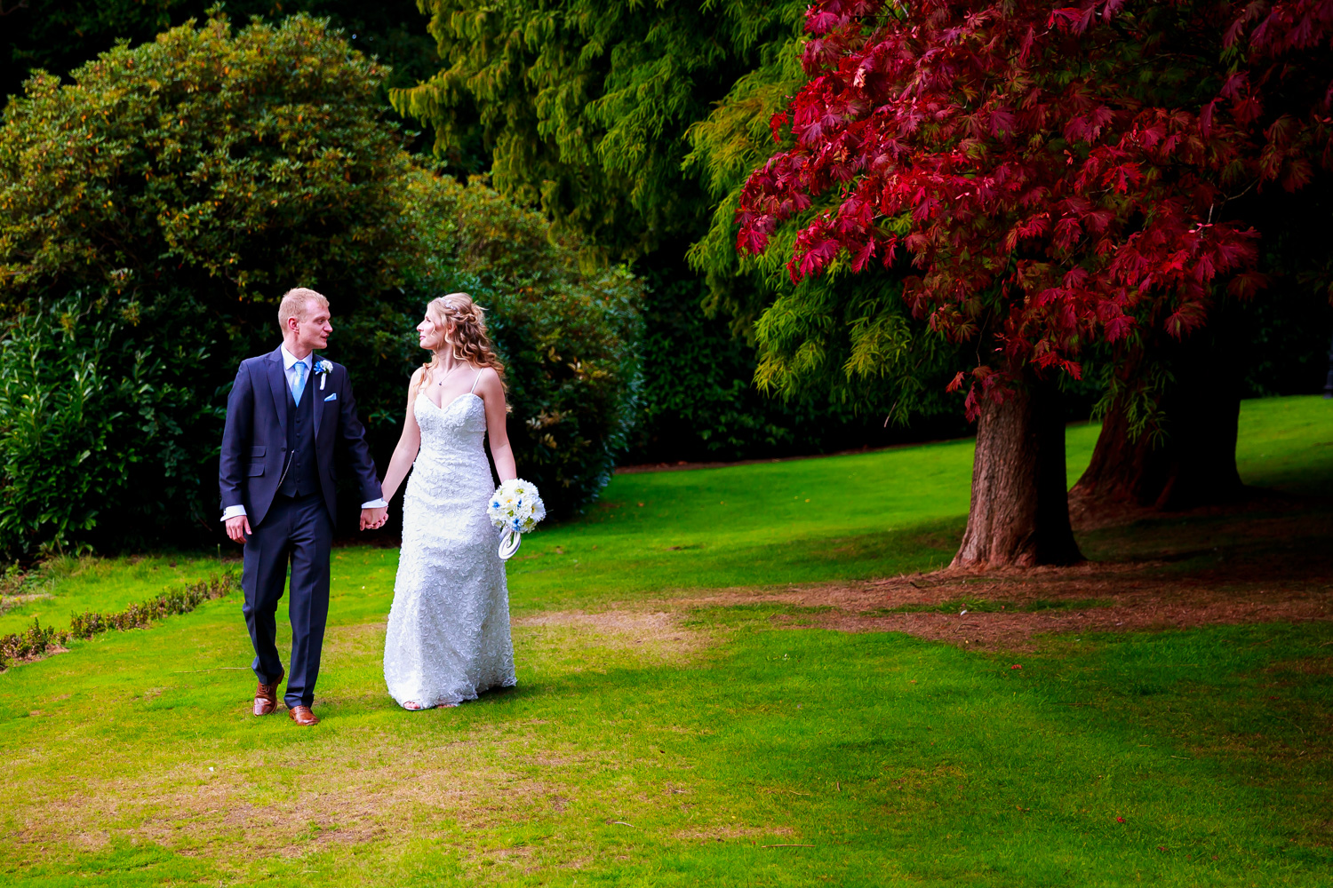 The bride and groom walking hand in hand in the beautiful grounds