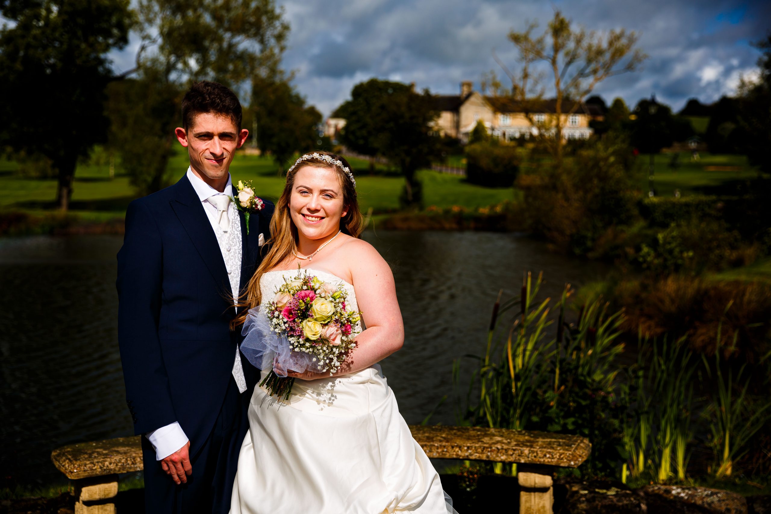 The bridge and groom posing for a couple photograph overlooking horsely lodge lake
